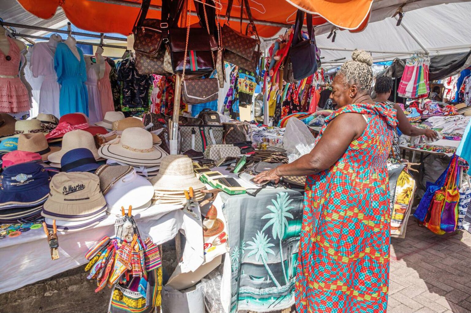 Local vendors selling crafts and fresh produce at a colorful market in Marigot, St. Maarten.